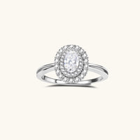 Sterling silver ring with oval moissanite center stone surrounded by double halo of sparkling stones on neutral background.