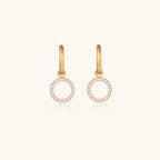 Gold-plated huggie hoop earrings with CZ-studded open circle charms on beige background