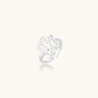 Sculptural sterling silver ring with organic branch design and textured surfaces on cream background