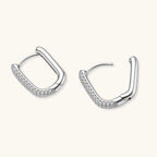 Close-up of platinum-plated sterling silver huggie hoops with pavé crystal setting on white background.